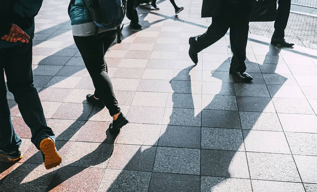A variety of people walking through an intersection from different directions